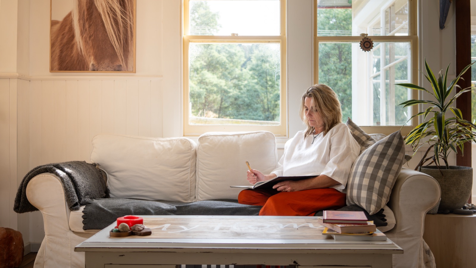 Annica Larsdotter writing on a sofa in natural window light